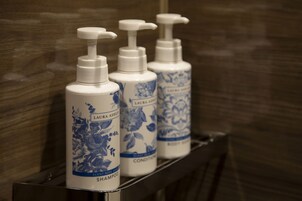 Tres botellas de acondicionador y champú Laura Ashley sobre una estantería.