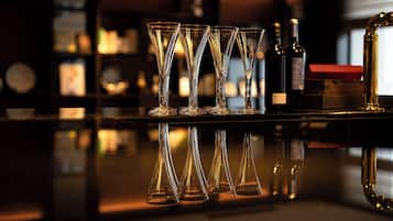 A bar area with multiple stemmed glasses and bottles of liquor on a reflective surface.