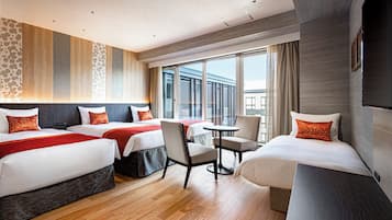 A hotel room with three beds, a small table, and a chair.
