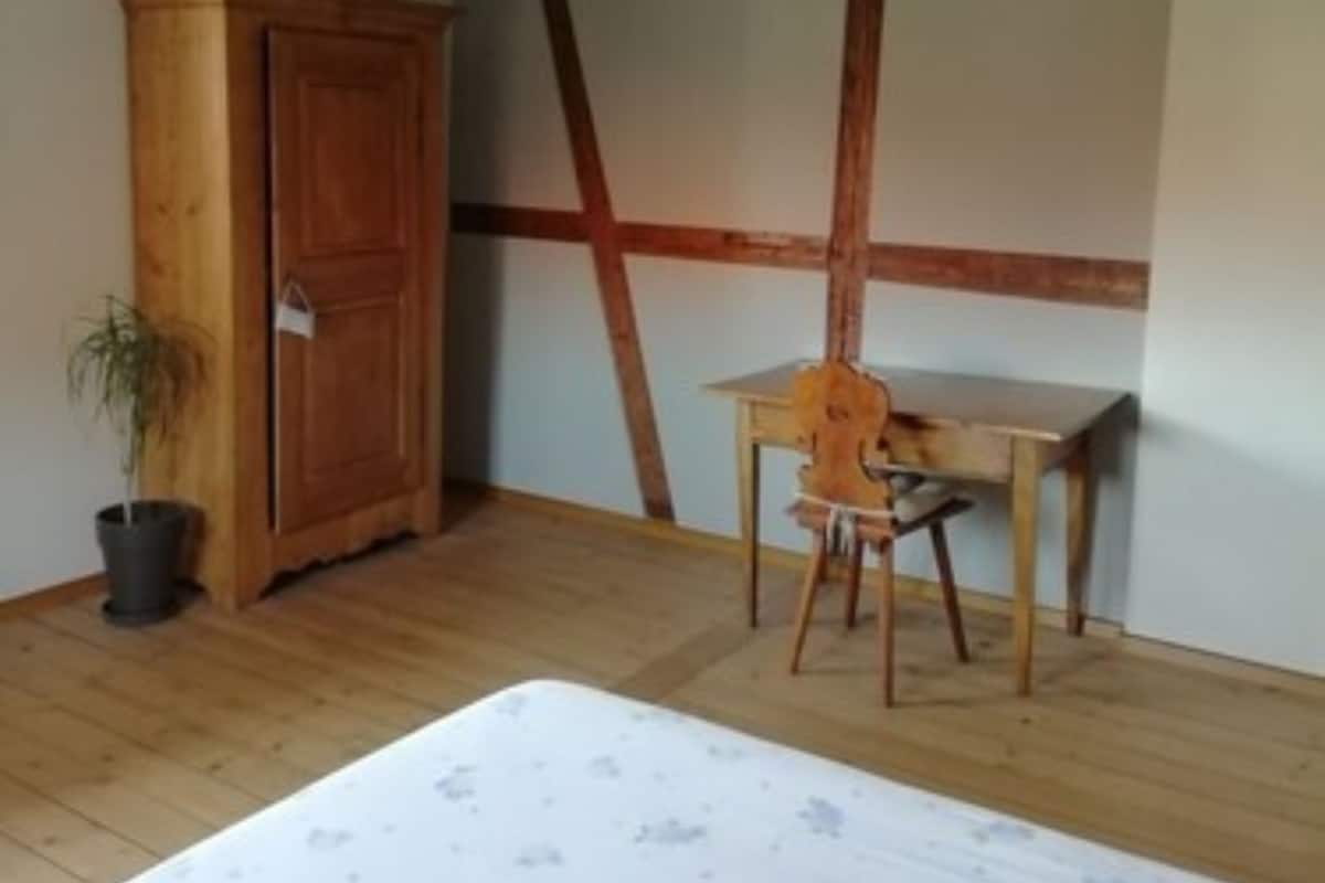 A bedroom with a wooden bed, a desk, and a wardrobe.