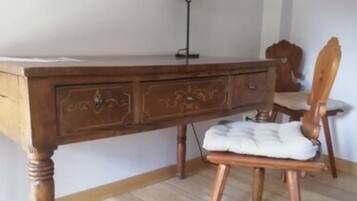 Ein Holztisch mit Schubladen, einer Lampe und einem Stuhl mit Sitzkissen.