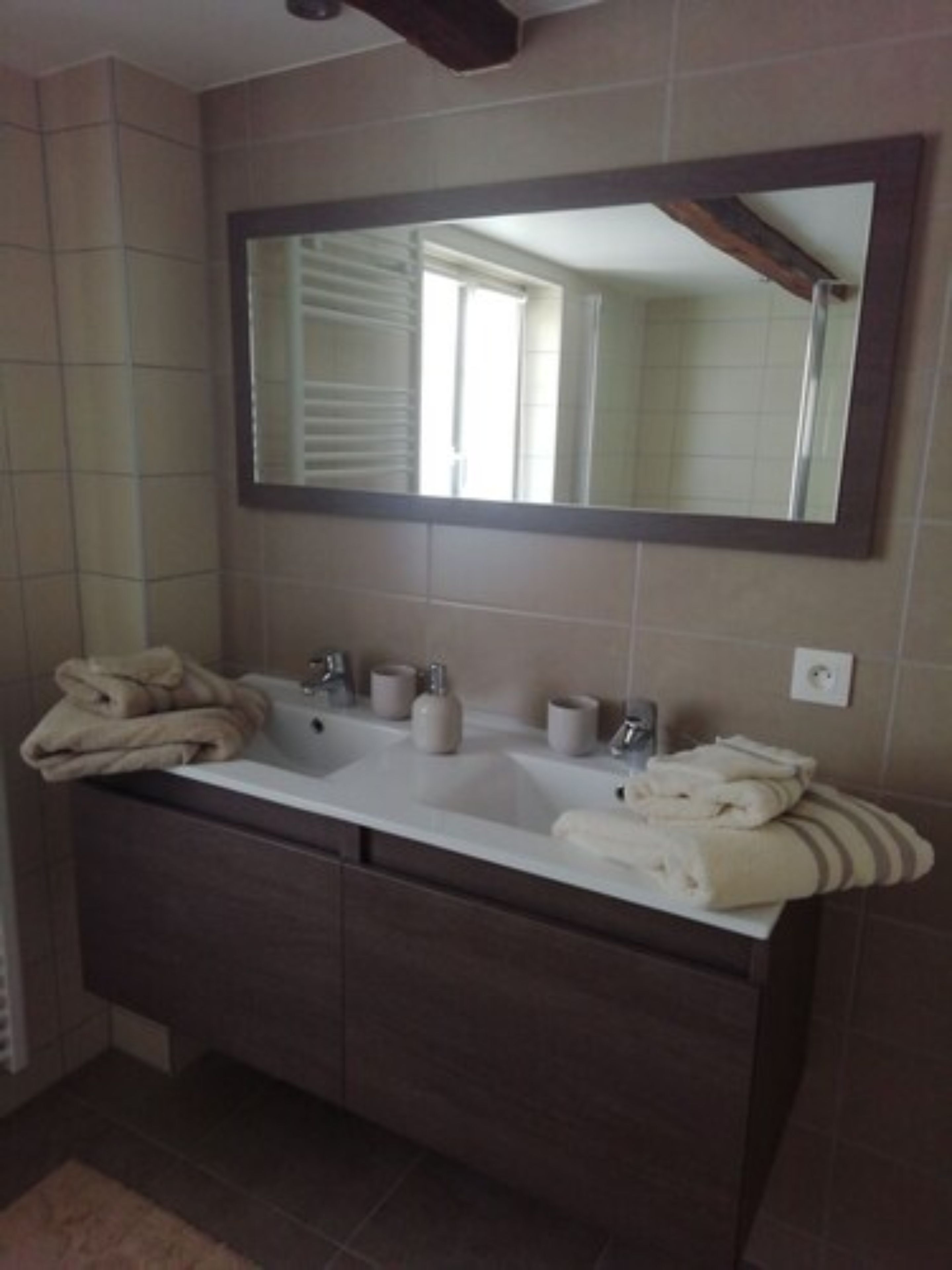 A bathroom with a double sink vanity, a large mirror, and towels.