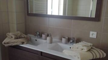 A bathroom with a double sink vanity, a large mirror, and towels.