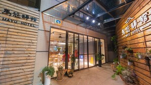 The exterior of the Mayu Hotel with wooden paneling and potted plants. - Mayu Hotel (Nangan)