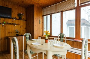 A wooden interior with a round dining table, white chairs, and a TV mounted on the wall. - Sun City Hostel (Kyiv)