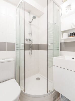 A modern bathroom with a glass-enclosed shower, a toilet, and a sink. - Résidence Louvre - Bellan (Paris)