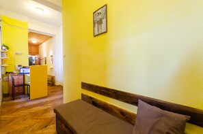 A room with a wooden bench, a yellow wall, and a framed picture.