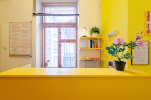 A reception area with a yellow counter, a wooden door, and a bulletin board with notices.