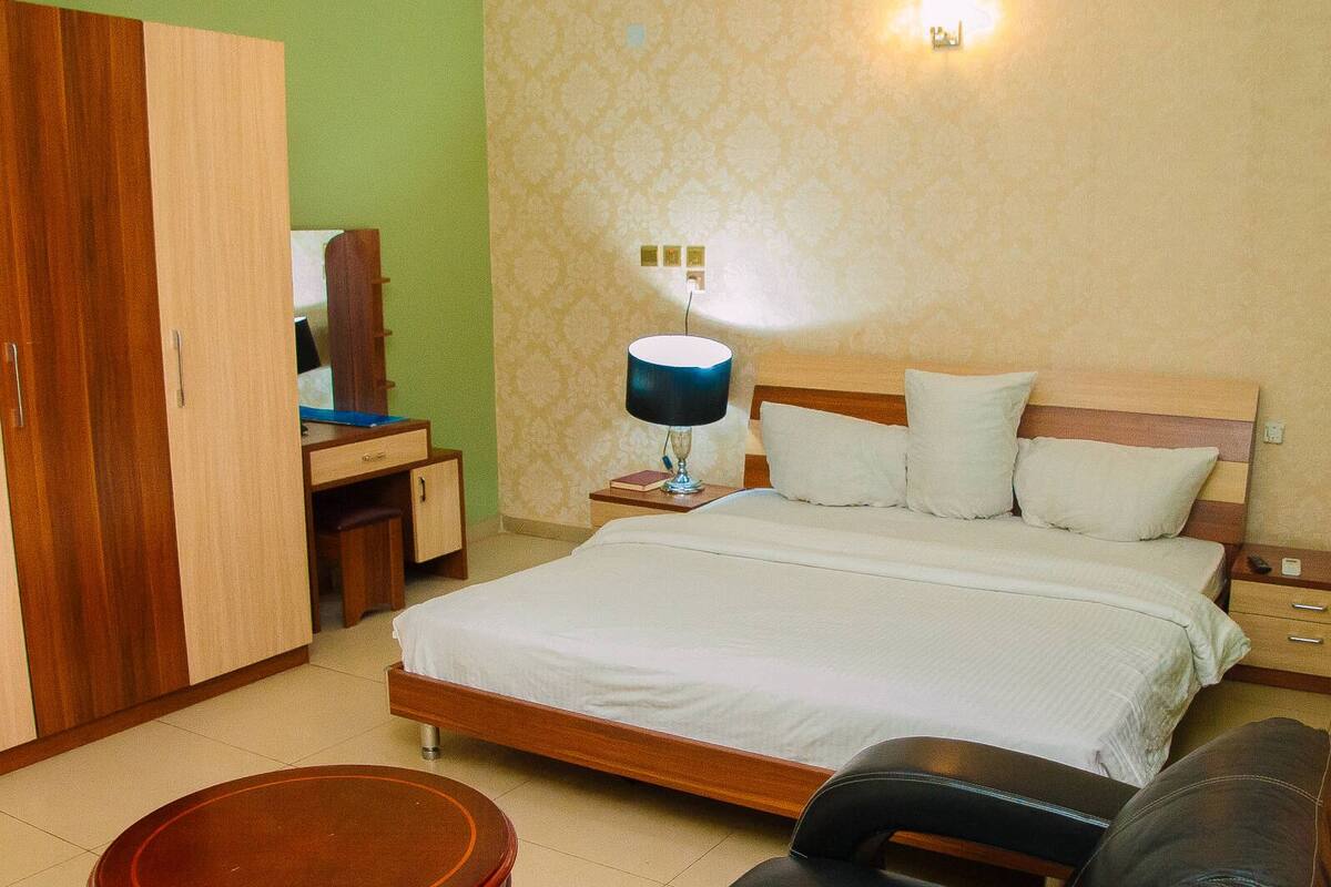 A bedroom with a bed, bedside table, lamp, and a wardrobe.