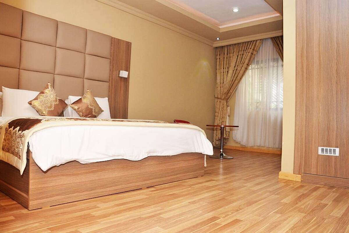 A spacious bedroom with a large bed, wooden headboard, and a wooden floor.