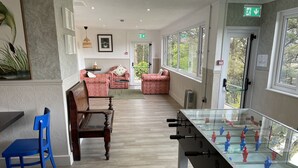 A room with a foosball table, a blue chair, and a sofa set. - The Elmfield (Ilfracombe)