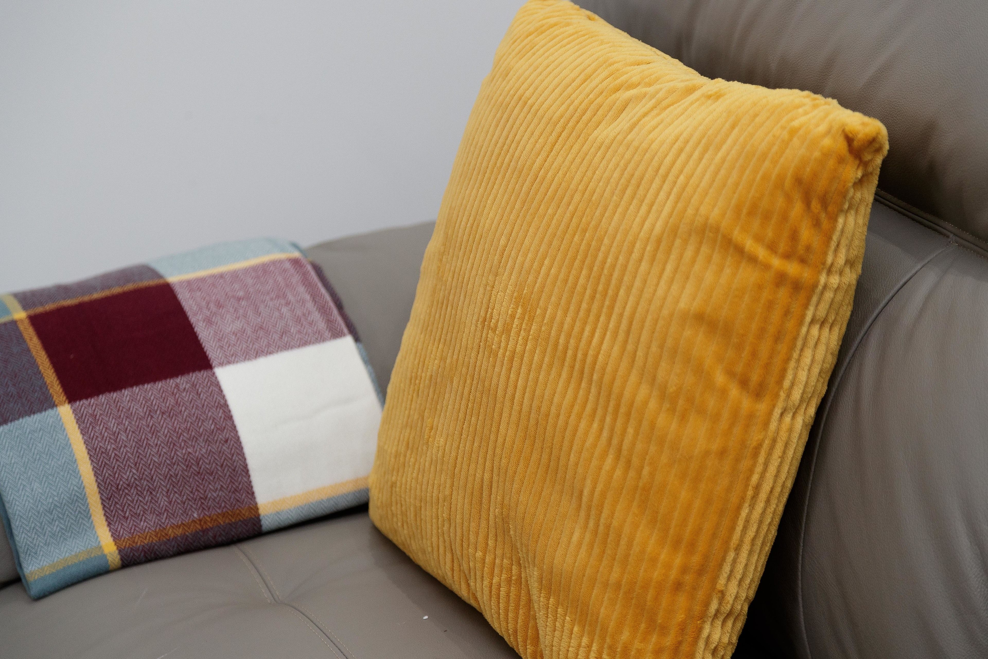 A grey sofa with two cushions, one yellow and one multicolored.