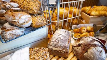 A variety of breads and pastries displayed in baskets and on a wooden table.