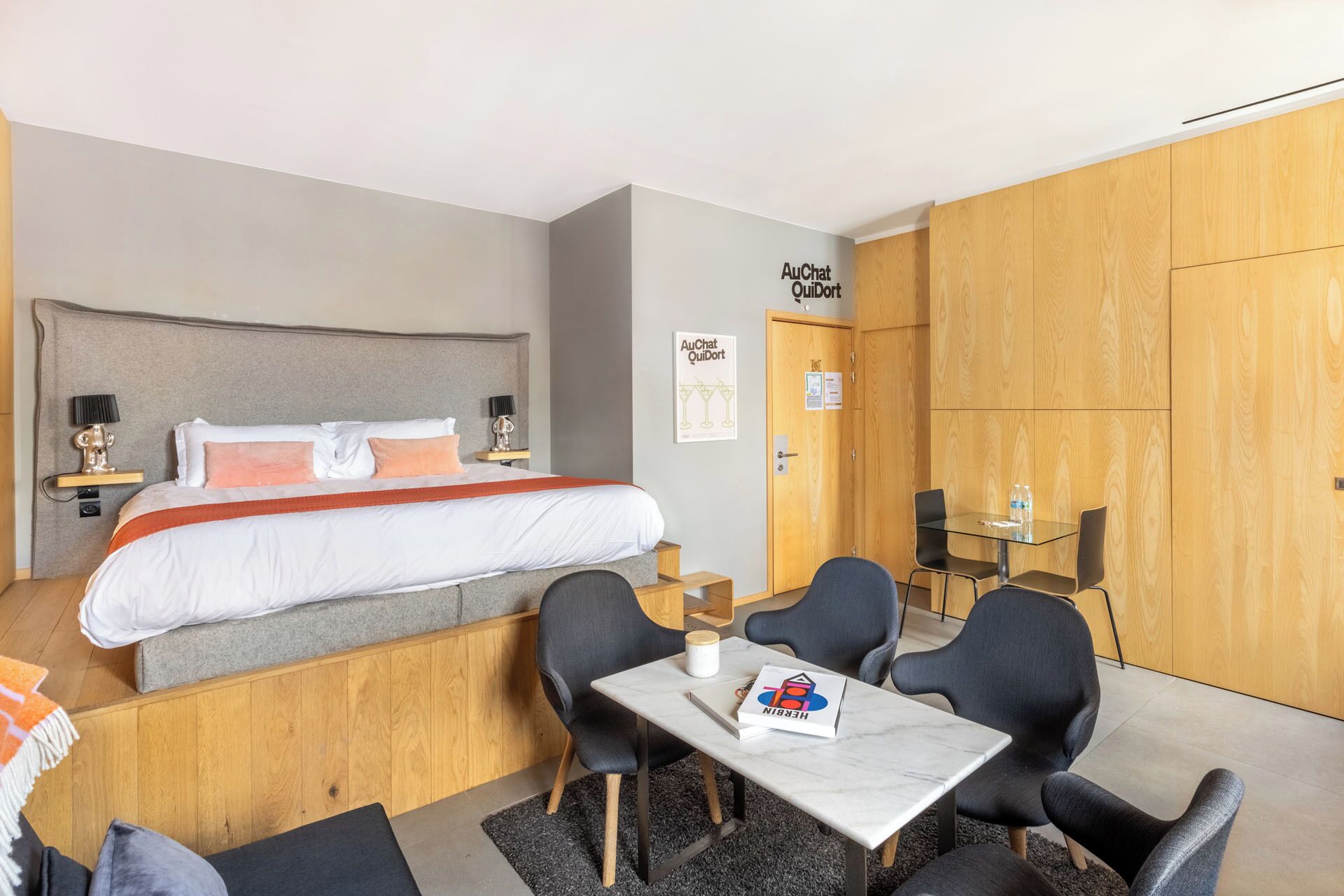 Ein Hotelzimmer mit einem Bett, Nachttischen, einem Schreibtisch mit Stühlen und einem Holzschrank.