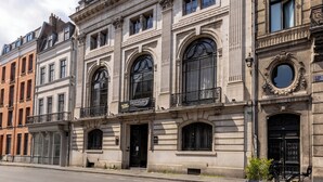 A historic building with large arched windows, a black iron gate, and a bicycle parked outside. - Au Chat Qui Dort Lille - Thiers (Lille)