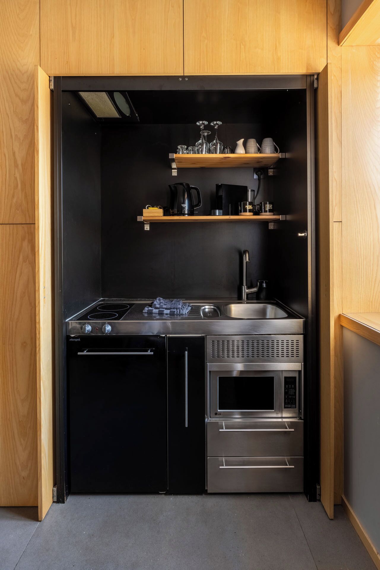 A compact kitchen with a stove, sink, and built-in microwave.