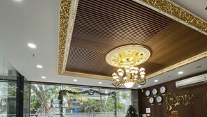 Zona de recepción de un hotel con diseño moderno, que incluye un mostrador de recepción, área de descanso y elementos decorativos en el techo.