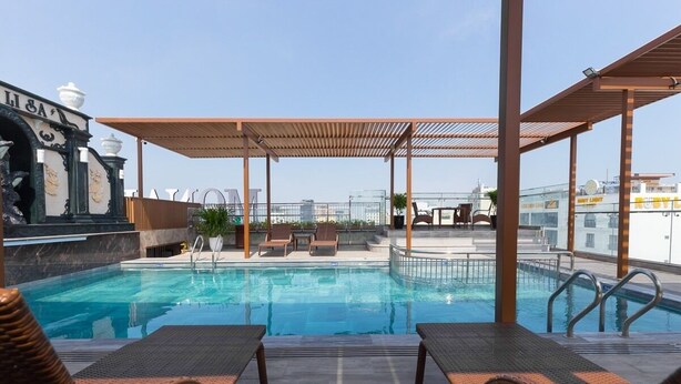 Un área de piscina en la azotea con sillones de descanso y una pérgola.