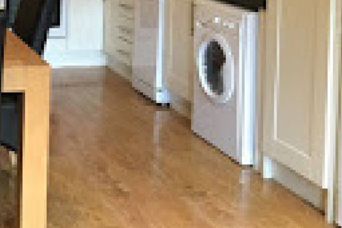 A kitchen with a wooden table, chairs, a washing machine, and a dishwasher.