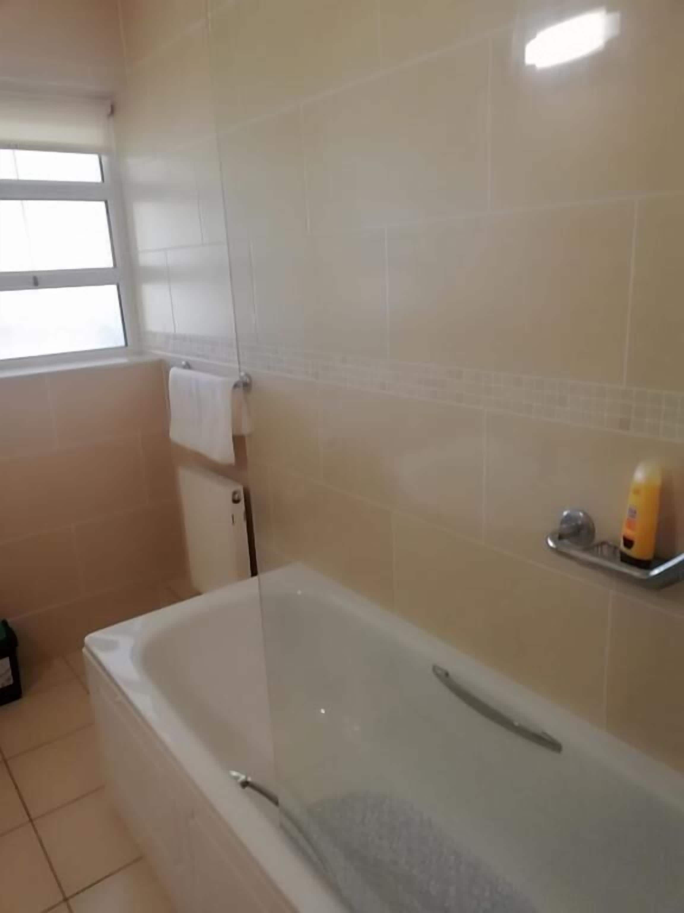Un baño con bañera, ventana y toallero.