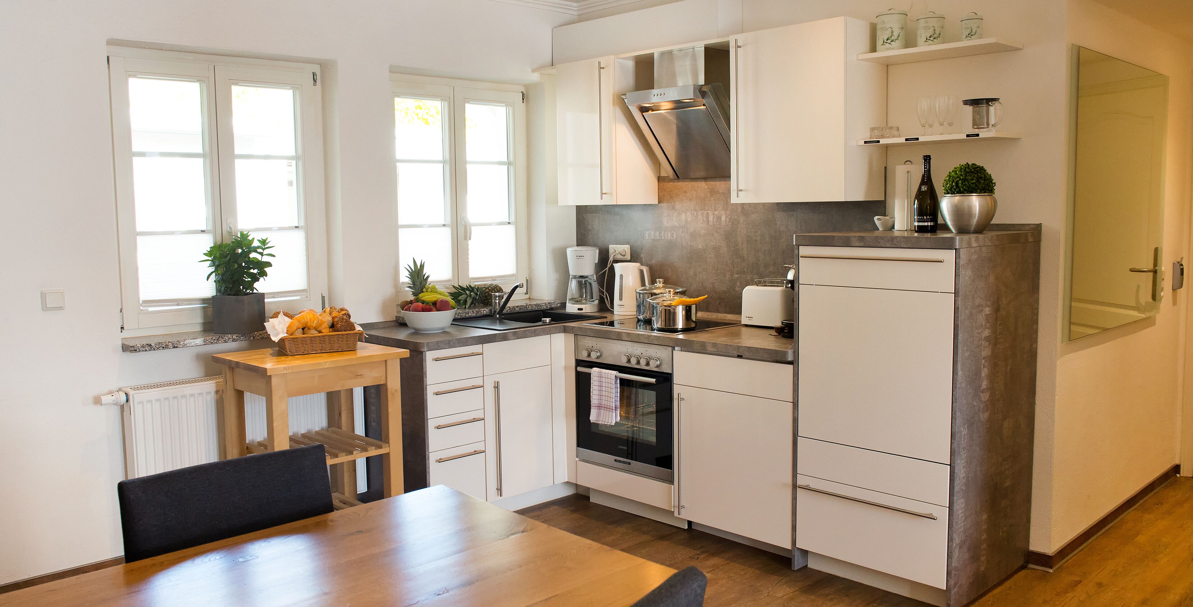 A modern kitchen with white cabinets, a built-in oven, and a coffee maker.