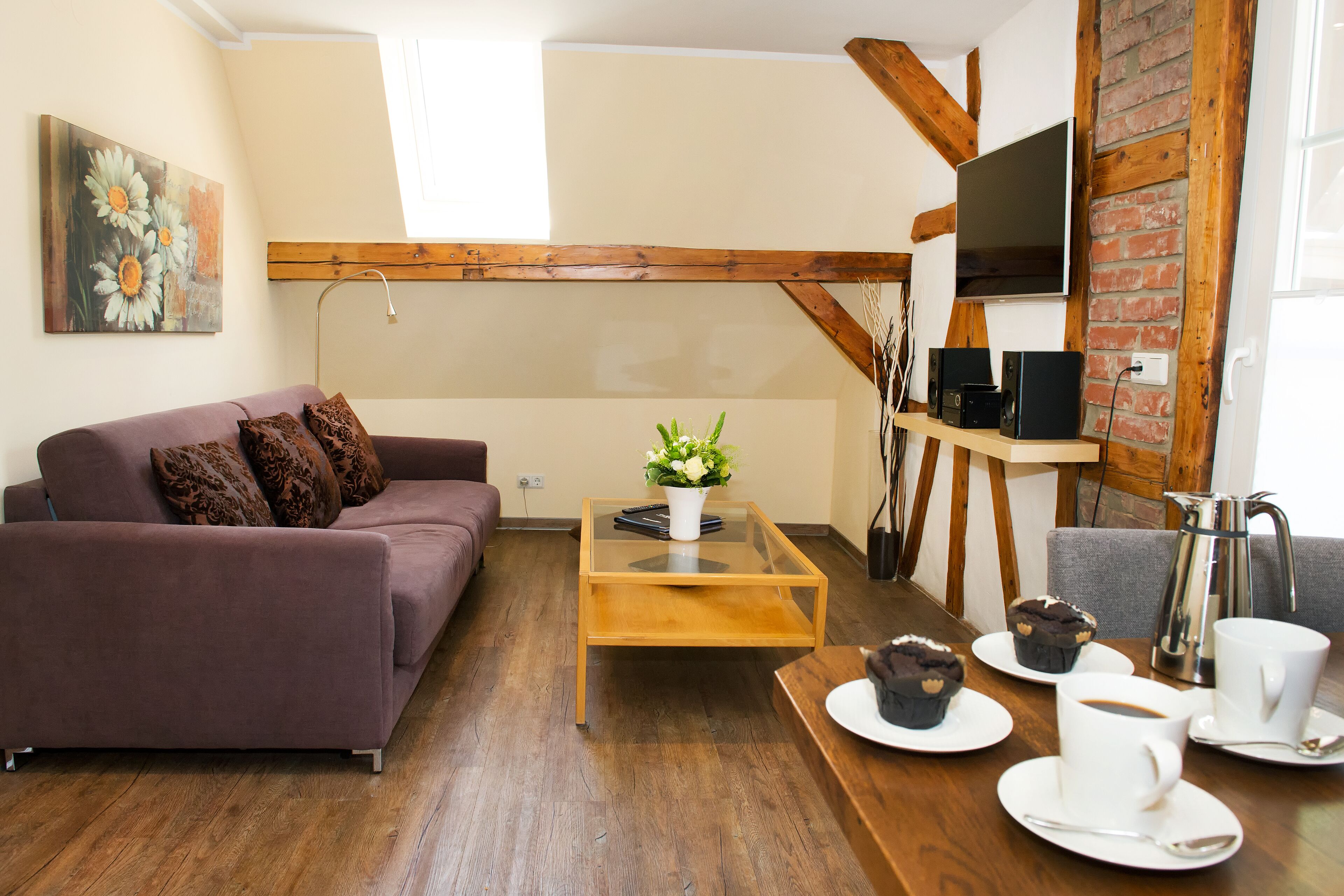 A living room with a sofa, coffee table, and a TV mounted on a brick wall.