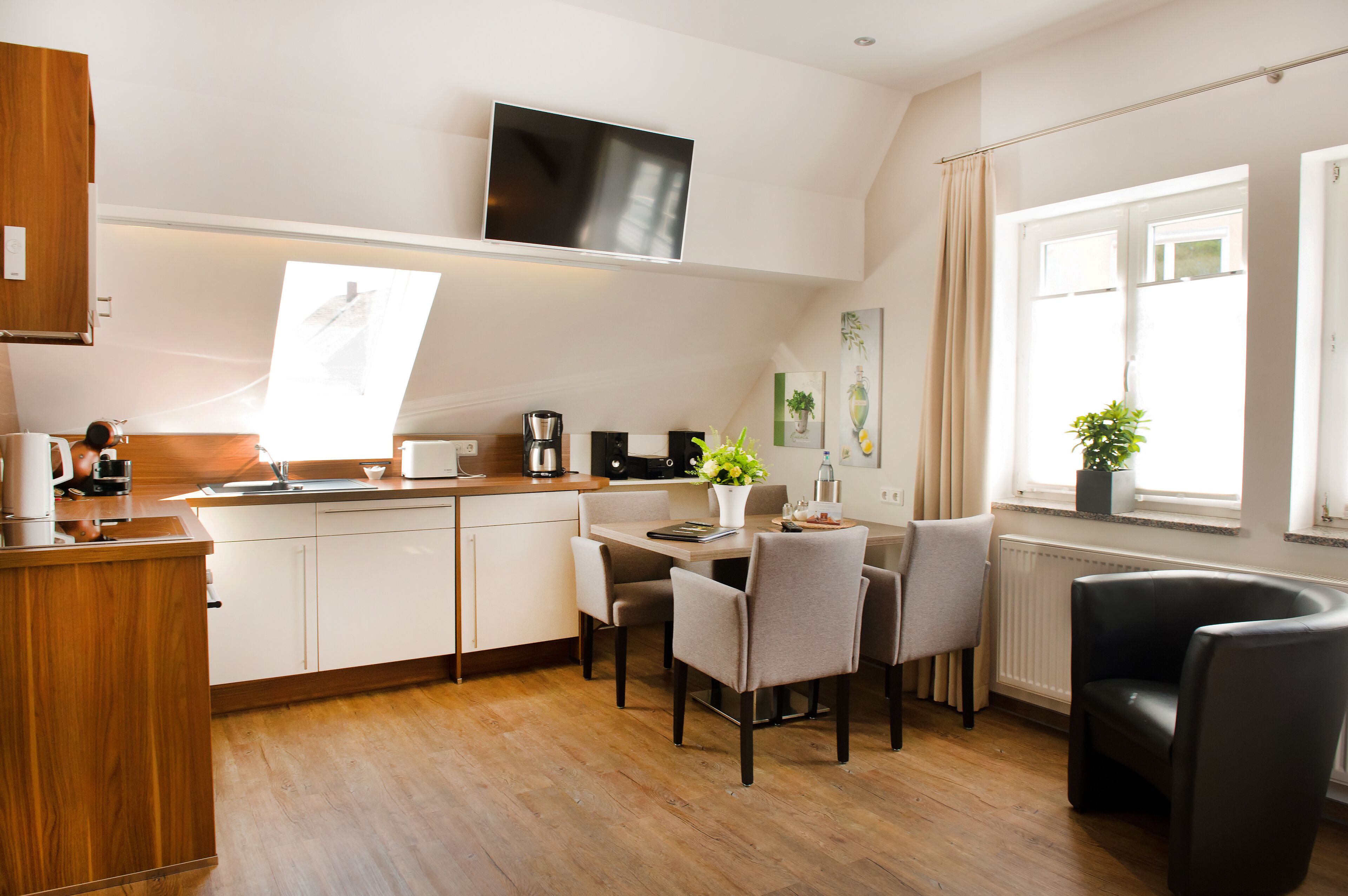 A modern kitchen with white cabinets, a wooden countertop, and a dining area with a table and chairs.