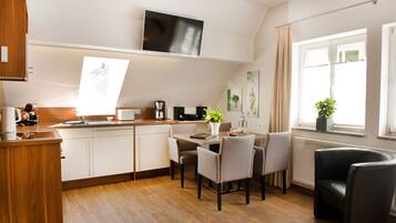 A modern kitchen with white cabinets, a wooden countertop, and a dining area with a table and chairs.