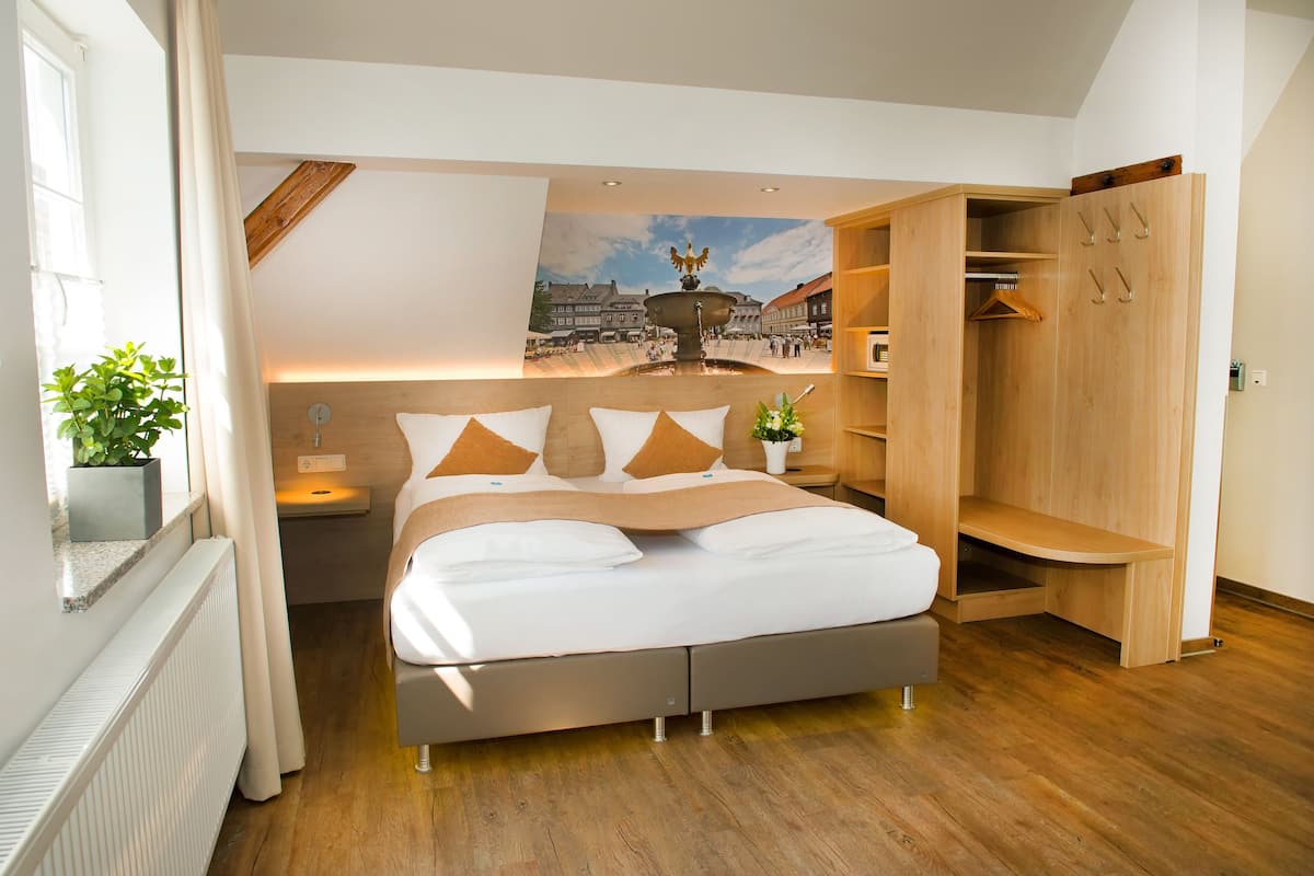 Een moderne slaapkamer met een bed, een houten garderobe en een stadsgezicht op de muur.