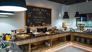 Espaço de café da manhã em hotel, com uma lousa, comidas de café da manhã e uma máquina de café.