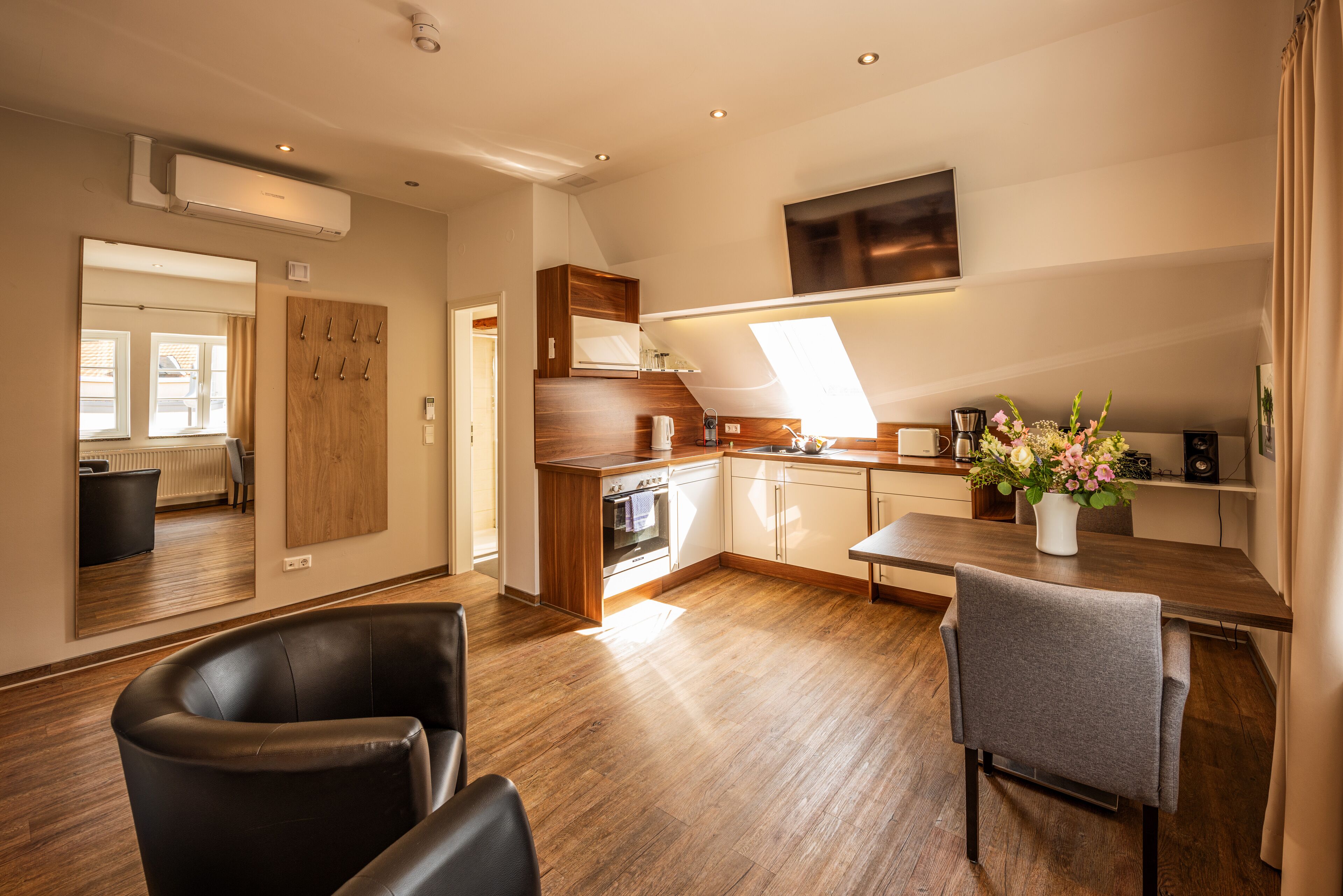 A modern kitchen with a wooden countertop, built-in oven, and a dining area with a table and chairs.