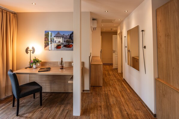A modern hotel room with a wooden floor, a desk with a chair, a lamp, and a framed picture on the wall. - City Appartments Am Wall (Goslar)