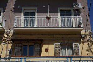 A building with a balcony, a window with shutters, and an air conditioning unit. - B&B Nodo Francescano (Porto Empedocle)