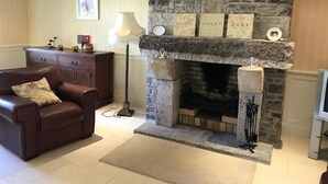 Una sala de estar acogedora con chimenea de piedra, un sofá de cuero y un aparador de madera.