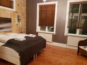 A bedroom with a bed, a radiator, a window with blinds, and a chair. - Casa Apartments (Reykjavik)