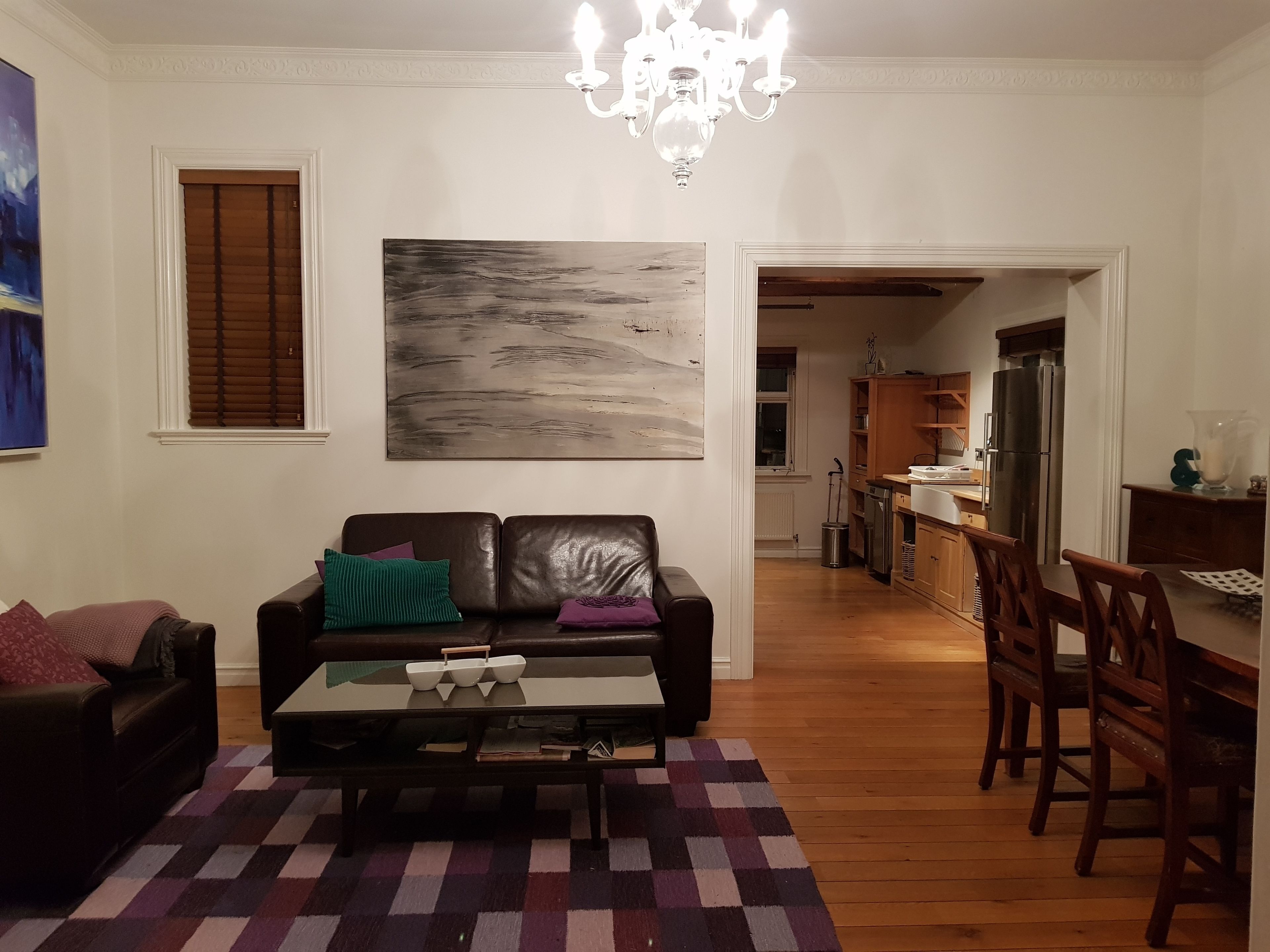 A living room with a sofa, coffee table, and a painting on the wall.