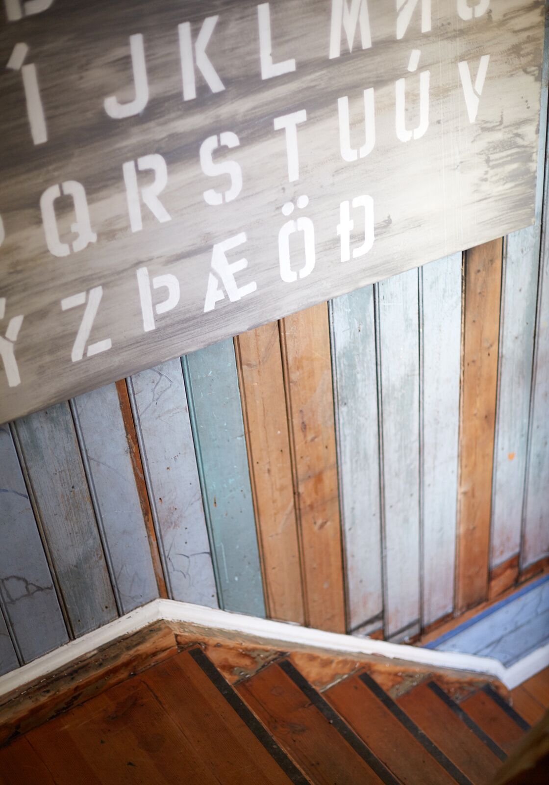 Une enseigne en bois avec des lettres blanches, fixée à un mur en bois composé de planches verticales.