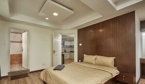 Une chambre à coucher avec un lit, une armoire en bois et une vue sur la cuisine.