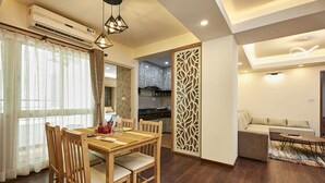 Un salon moderne avec une table à manger en bois, un canapé et une cuisine en arrière-plan.