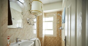 Une salle de bain équipée d’un lavabo, d’un miroir, de toilettes et d’une douche.