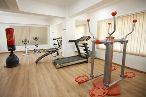 Une salle de sport équipée de tapis de course, d’appareils de musculation et d’un sac de frappe.