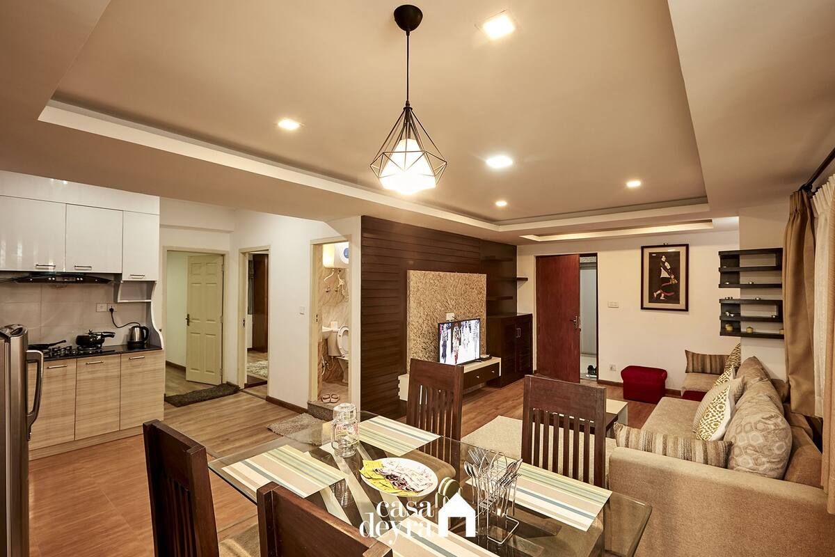 A modern living room with a glass dining table, wooden chairs, and a red sofa.