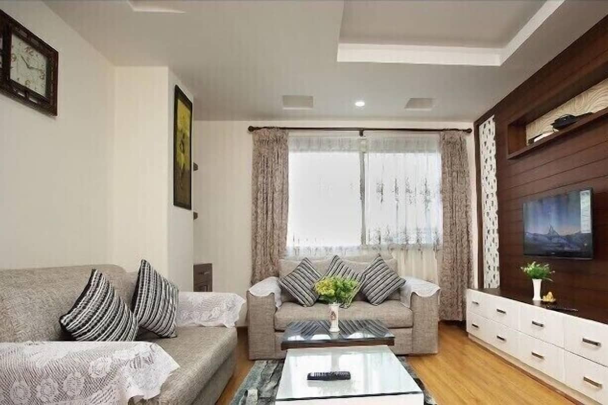 A living room with a sofa, a coffee table, a TV, and a wooden wall.