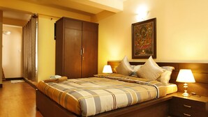 A bedroom with a large bed, wooden wardrobe, and two bedside lamps. - Kathmandu Heritage Home by Casa Deyra (Kathmandu)
