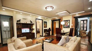 A spacious living room with a fireplace, a television, and a dining area. - Kathmandu Heritage Home by Casa Deyra (Kathmandu)