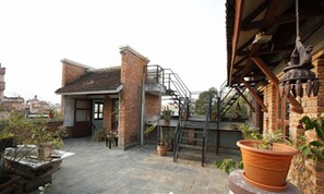 Relax on the rooftop terrace with a metal staircase leading to an upper level, surrounded by potted plants and a small table.