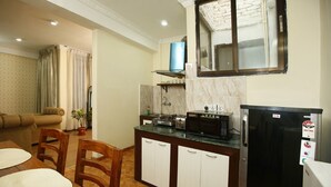 A compact kitchen with a refrigerator, microwave, and stove. There is a dining area with a table and chairs.