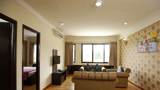 A living room with a sofa, TV, and a window with curtains.