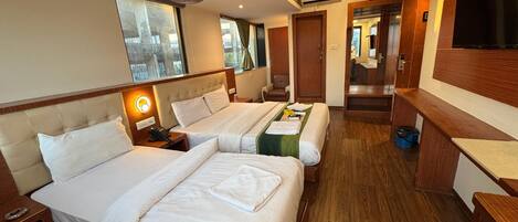 A hotel room with two beds, a desk, a chair, a TV, and a bathroom visible through an open door.