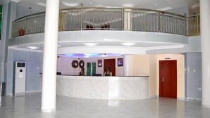 A spacious lobby with a marble floor, a reception desk, and a second-floor balcony with a metal railing. - Gold Crown Hotel (Owerri)